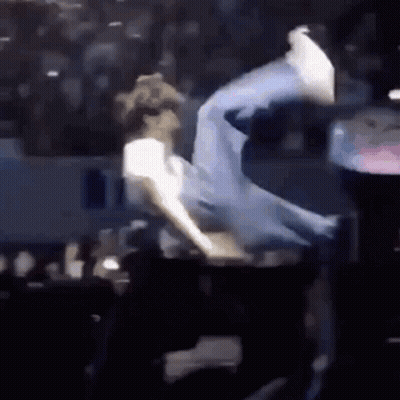 A Man Is Doing A Trick On A Stage In Front Of A Crowd Of People . GIF