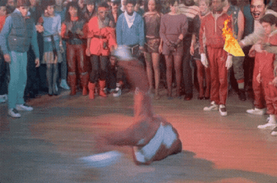 A Man Is Doing A Trick On The Floor In Front Of A Crowd Of People GIF