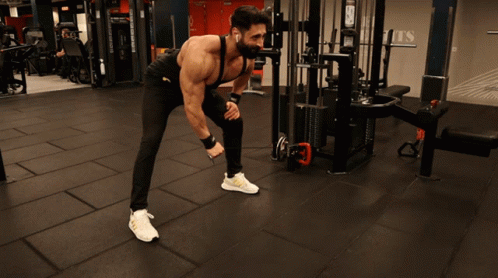 A Man Is Doing Exercises In A Gym With A Sign On The Wall That Says Sports GIF