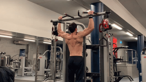 A Man Is Doing Pull Ups In A Gym With A Machine That Says ' Smith ' On It GIF