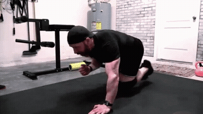 A Man Is Doing Push Ups On A Mat In A Gym While Holding A Roller . GIF