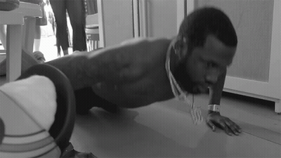A Man Is Doing Push Ups On The Floor While Wearing A Watch GIF