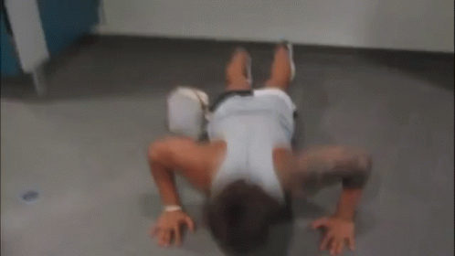 A Man Is Doing Push Ups On The Floor With A Purse On The Floor . GIF