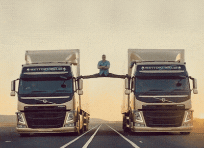 A Man Is Doing Splits Between Two Volvo Trucks On A Highway GIF