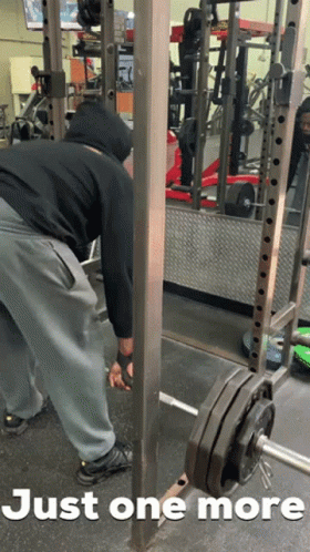 A Man Is Doing Squats In A Gym With The Words Just One More Behind Him GIF