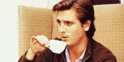 A Man Is Drinking A Cup Of Coffee From A White Cup GIF