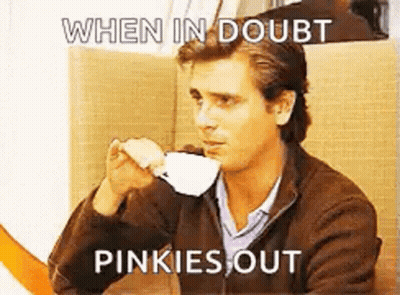 A Man Is Drinking A Cup Of Coffee While Sitting At A Table With A Meme . GIF
