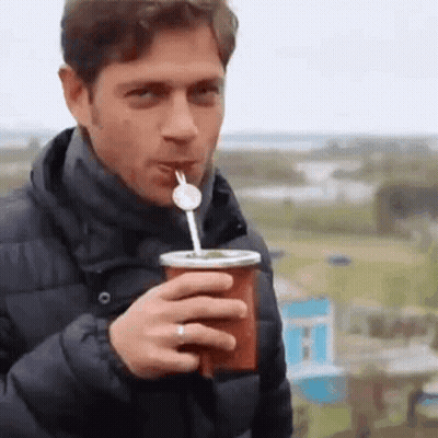 A Man Is Drinking A Drink With A Straw Through A Cup . GIF