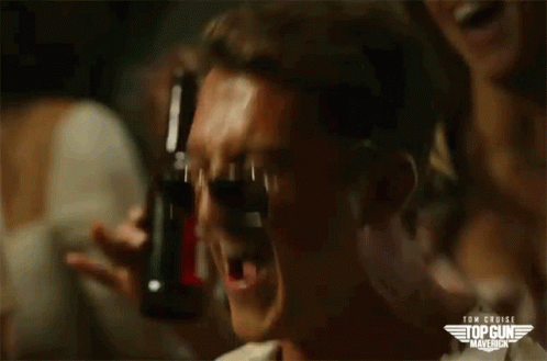 A Man Is Drinking From A Bottle With A Top Gun Maverick Logo On The Bottom GIF