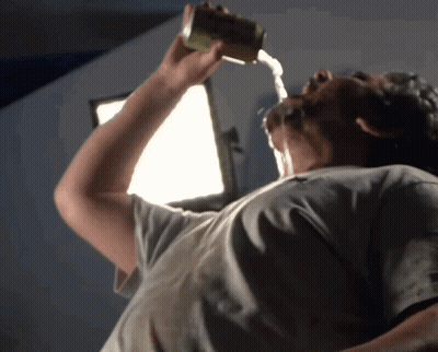 A Man Is Drinking From A Can With Water Pouring Out Of It Into His Mouth GIF