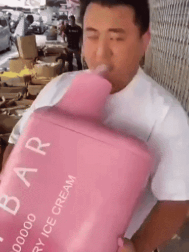 A Man Is Drinking From A Pink Container That Says Strawberry Ice Cream On It GIF