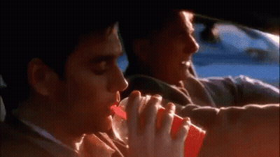 A Man Is Drinking From A Red Cup While Sitting In A Car . GIF