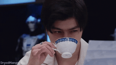 A Man Is Drinking From A White Cup With A Blue And White Design On It . GIF