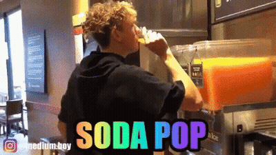 A Man Is Drinking Orange Juice From A Soda Pop Machine GIF