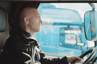 A Man Is Driving A Blue Truck And Looking Out Of The Window GIF