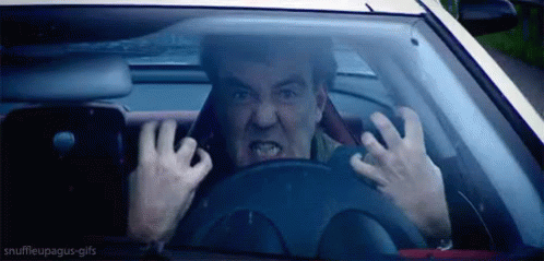 A Man Is Driving A Car And Making A Funny Face While Holding The Steering Wheel . GIF