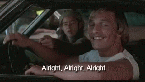 A Man Is Driving A Car And Smiling While Another Man Is Sitting In The Back Seat . GIF