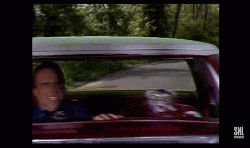 A Man Is Driving A Car And Smiling While Looking Out The Window . GIF