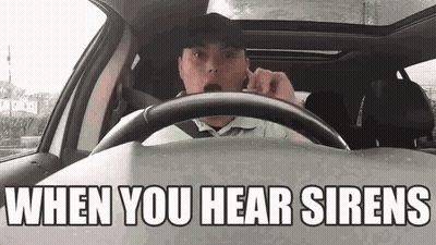 A Man Is Driving A Car And Talking On A Cell Phone While Wearing A Hat . GIF