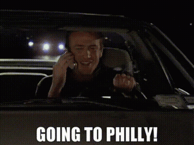 A Man Is Driving A Car And Talking On A Cell Phone With The Words Going To Philly Above Him GIF