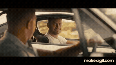 A Man Is Driving A Car And Talking To Another Man In The Driver 'S Seat . GIF