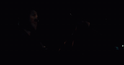 A Man Is Driving A Car At Night And Holding The Steering Wheel In His Hand . GIF