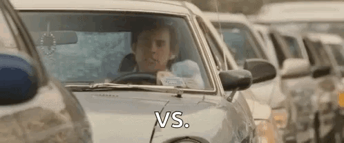 A Man Is Driving A Car In A Traffic Jam With The Words `` Vs '' Written On The Side . GIF