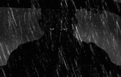 A Man Is Driving A Car In The Rain And Looking Out The Window . GIF