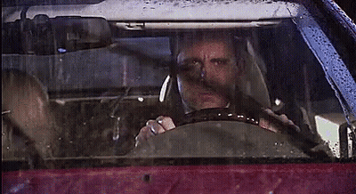 A Man Is Driving A Car In The Rain With A Woman Sitting In The Back Seat . GIF