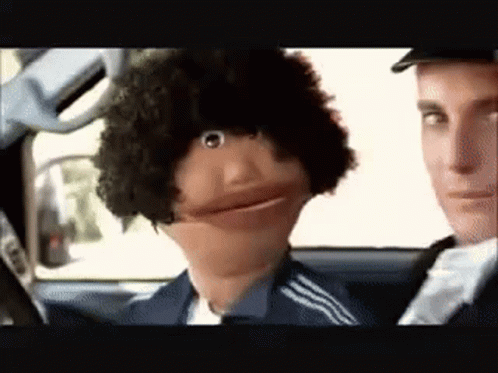 A Man Is Driving A Car Next To A Puppet With A Big Afro . GIF
