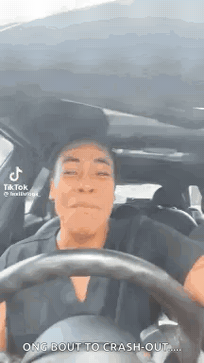 A Man Is Driving A Car With A Steering Wheel And Making A Funny Face . GIF