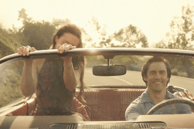 A Man Is Driving A Car With A Woman Sitting In The Back GIF