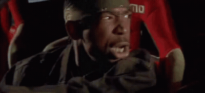A Man Is Driving A Car With Blood On The Steering Wheel And A Bandana On His Head . GIF