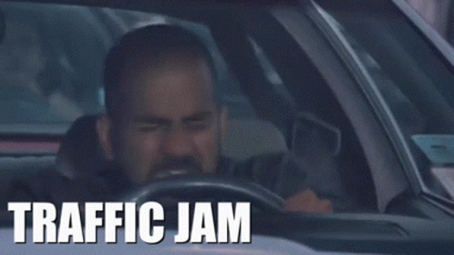 A Man Is Driving A Car With The Words Traffic Jam On The Dashboard . GIF