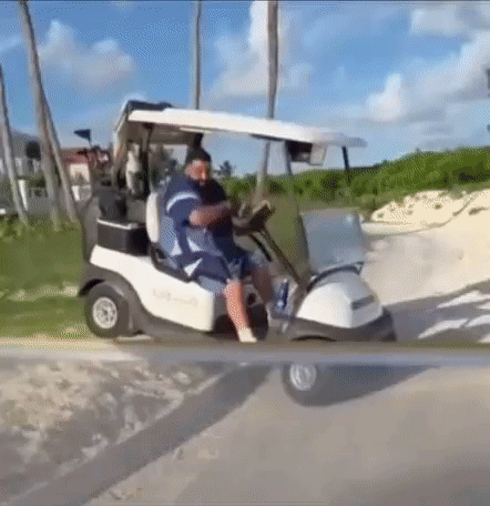 A Man Is Driving A Golf Cart Down A Road . GIF