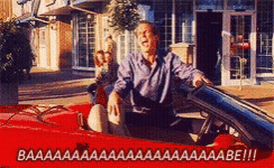 A Man Is Driving A Red Convertible With The Words Baaa On The Bottom Right GIF