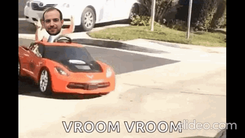 A Man Is Driving A Toy Car On A Street With A Man 'S Head Sticking Out Of It . GIF