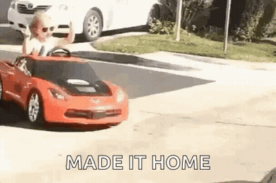 A Man Is Driving A Toy Car On A Street . GIF