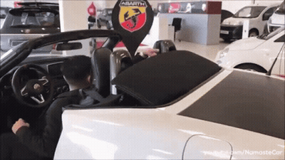 A Man Is Driving An Abarth Car In A Car Showroom GIF