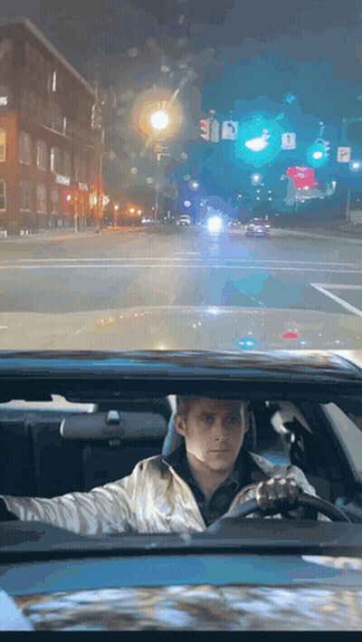 A Man Is Driving Down A Street At Night With A Sign That Says A On It GIF