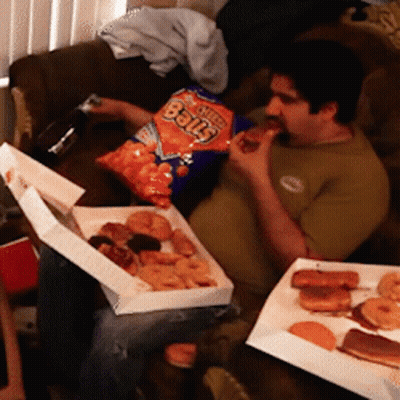A Man Is Eating A Bag Of Cheetos Balls While Sitting On A Couch GIF