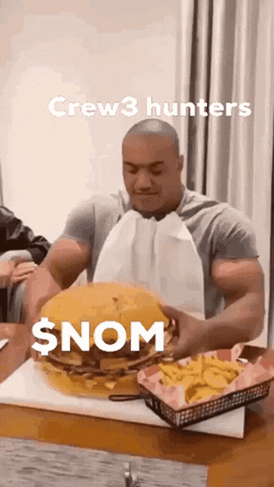 A Man Is Eating A Giant Hamburger And French Fries On A Table . GIF