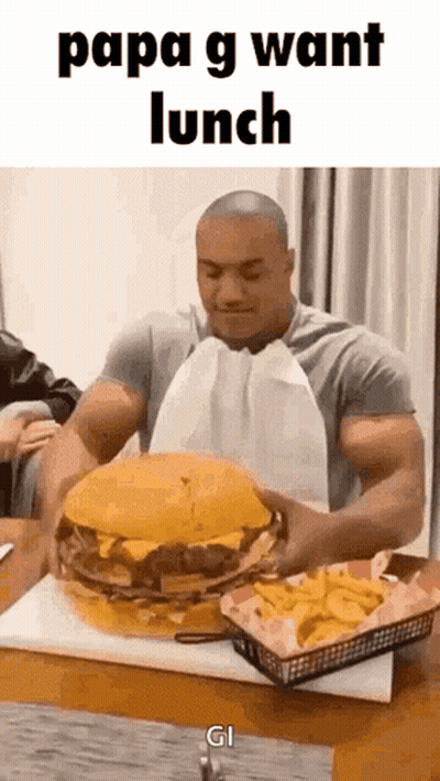 A Man Is Eating A Giant Hamburger And French Fries . GIF