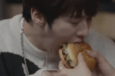 A Man Is Eating A Hamburger With His Eyes Closed . GIF