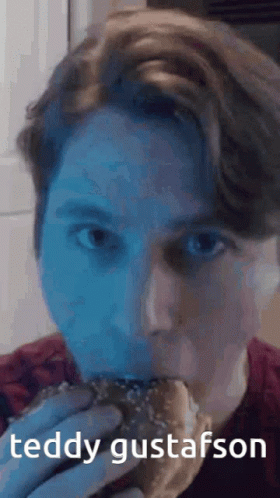 A Man Is Eating A Hamburger With The Name Teddy Gustafsson Written On The Bottom GIF
