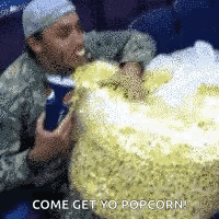 A Man Is Eating A Large Amount Of Popcorn And Says Come Get Yo Popcorn . GIF
