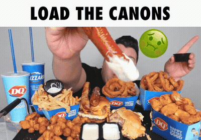 A Man Is Eating A Large Hot Dog With The Words Load The Canons Behind Him GIF