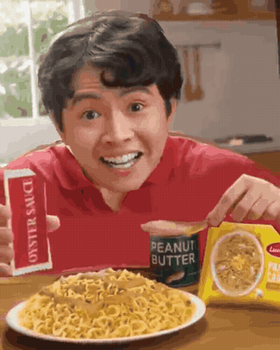 A Man Is Eating Noodles With Peanut Butter Sauce GIF