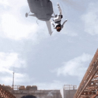 A Man Is Falling From A Helicopter In The Air GIF