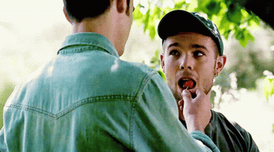A Man Is Feeding Another Man A Strawberry GIF